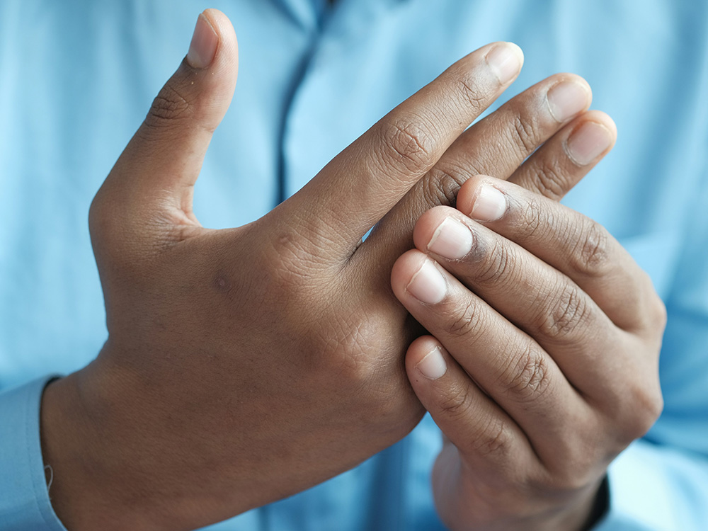 Patient mit Schmerzen im Daumengelenk und Fingerarthrose bei einer Untersuchung der Handfunktion